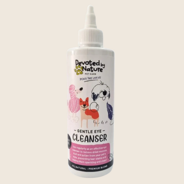 A white plastic bottle of Devoted by Nature Gentle Eye Cleanser for pets, featuring a white cap and a label with illustrations of a black and white dog, a pink cat, and a small red dog.